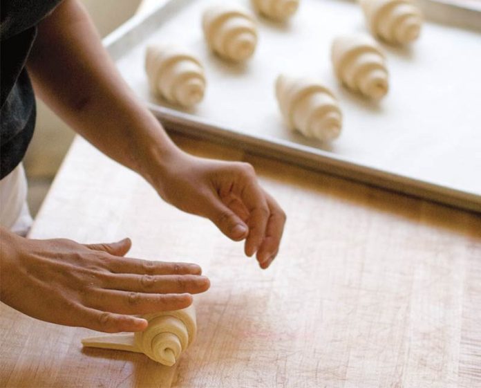 tartine bakery rolling croissant on wooden block
