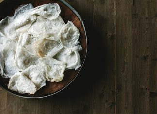 Lacy Kerala Style Appam Appam in brown bowl on wooden surface