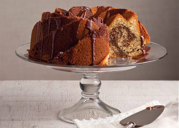 Peanut Butter and Chocolate Swirl Bundt Cake sliced on glass cake stand