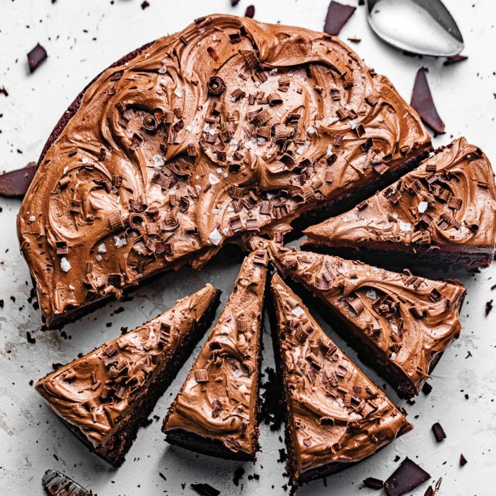 One-Bowl Chocolate Cake with Chocolate Buttercream on white background half sliced