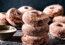 Spiced Apple Cider Doughnuts Spiced apple cider doughnuts on dark surface with cinnamon sugar spread