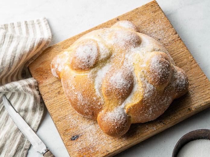 pan de muerto baking school in depth module. bread sugared on wooden cutting board
