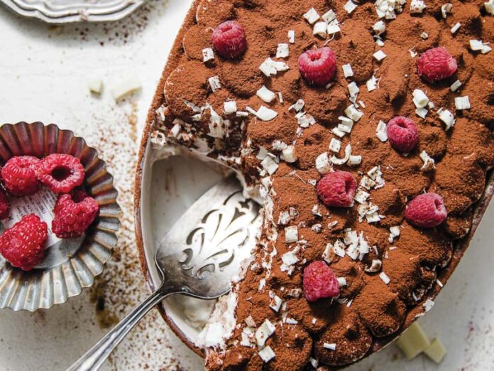 White Chocolate Raspberry Tiramisu in baking dish with silver plate of raspberries