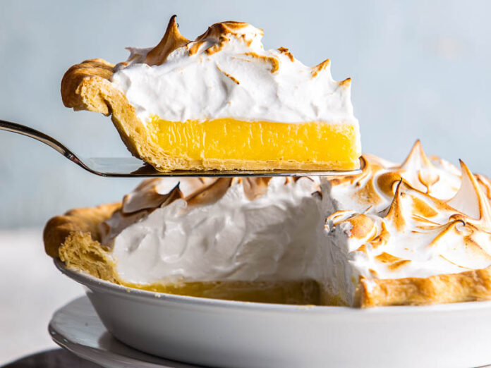 mile-high lemon meringue pie on server lifting out of pie dish.