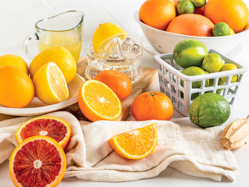 Citrus stacked on white marble with juice and zest