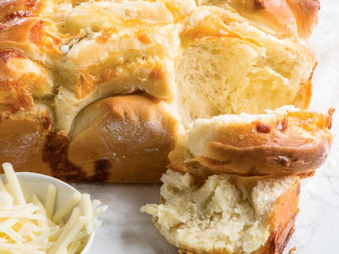 Four Cheese Pull-Apart Milk Bread Loaf on Marble with Cup of Shredded Cheese
