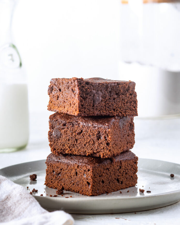 Cakey Brownies staked on plate with milk pitcher in background
