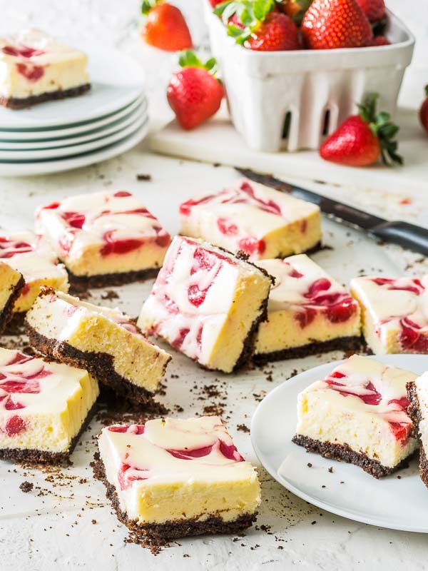 Strawberry Swirl Cheesecake Bars with strawberries in crate in the background