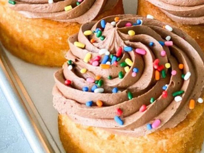 Vanilla Buttermilk Mini Cakes with Chocolate Buttermilk Frosting and Multi-Color Sprinkles on Parchment on Baking Sheet