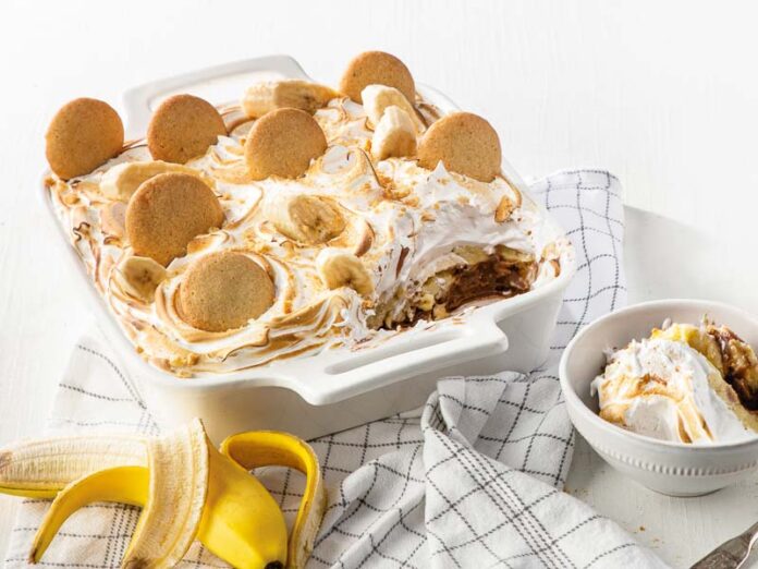 Chocolate-Hazlenut-Banana Pudding in white baking dish with banana, dish towel, and white bowl of pudding