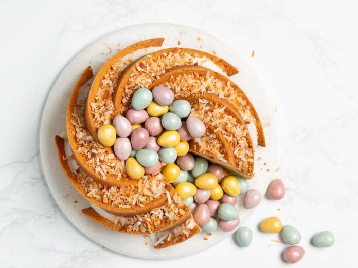 Almond Bundt Cake with Coconut Glaze and Multicolored Mini Chocolate Eggs on marble