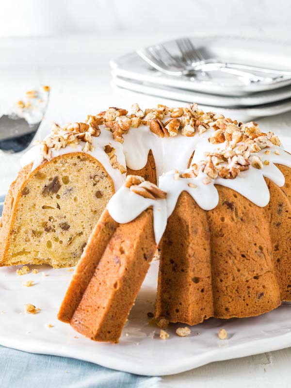 Butter Pecan Pound Cake on white serving platter with plates and forks in backgrounds