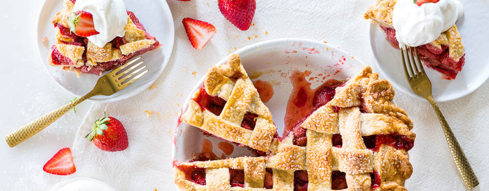 6 Pie Perfections for Your Easter Extravaganza Strawberries & Cream Pie in white pie dish with two slices on white plates with forks