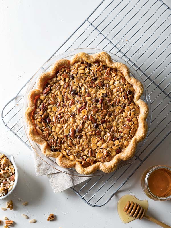 Honey Nut Pie on wire cooling rack with bowl of nuts and bowl of honey