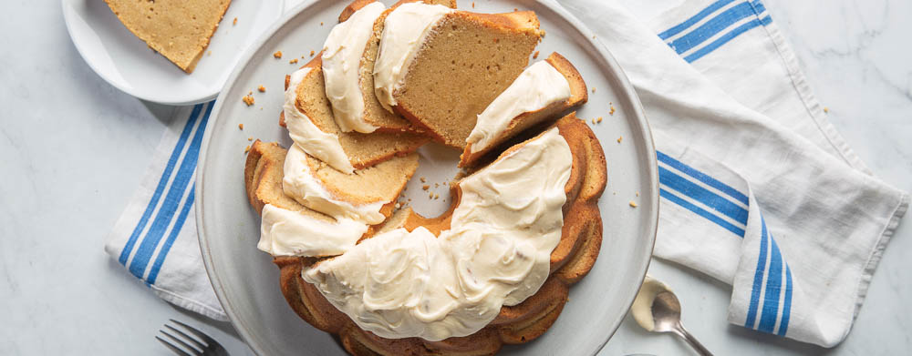 Irish Cream Pound Cake on white plate with slice of cake and striped dish towel