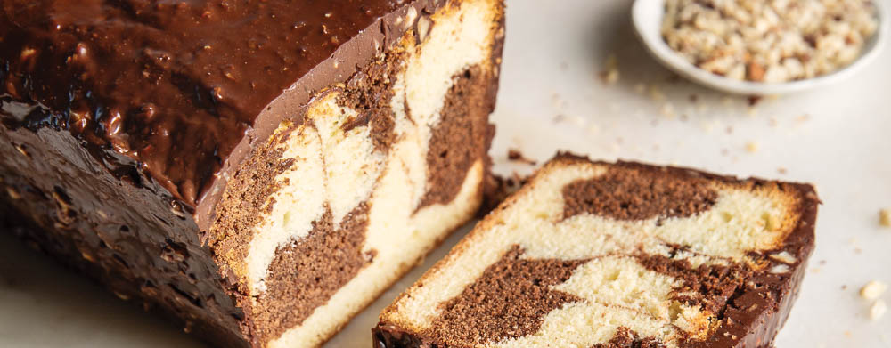 French Marble Pound Cake on white counter with bowl of hazelnuts