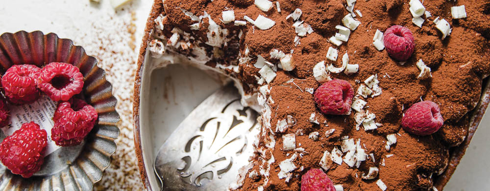 White Chocolate Raspberry Tiramisu in baking dish with silver plate of raspberries
